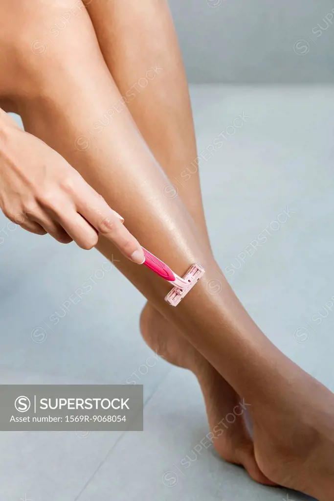 Woman shaving legs, cropped