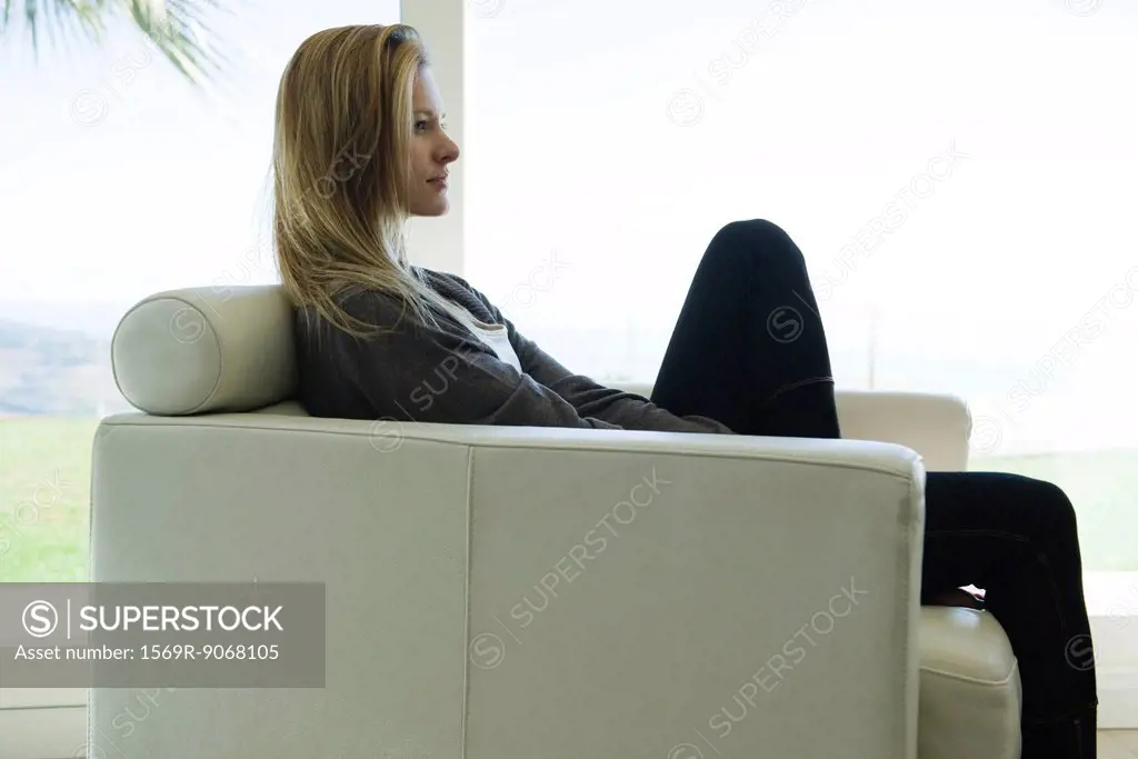 Woman sitting in armchair, side view