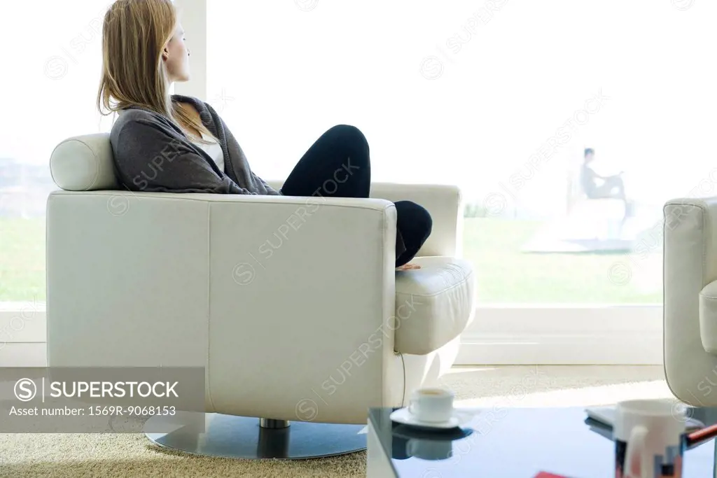 Woman relaxing in armchair, gazing out window