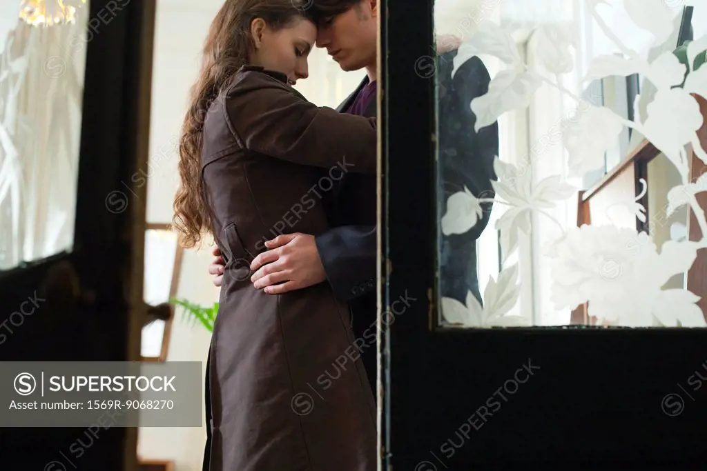 Couple embracing, viewed through open door