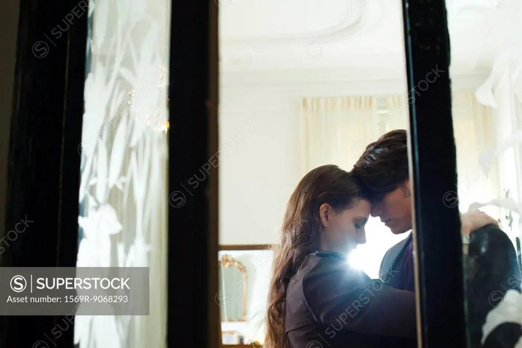 Couple embracing, viewed through open doors