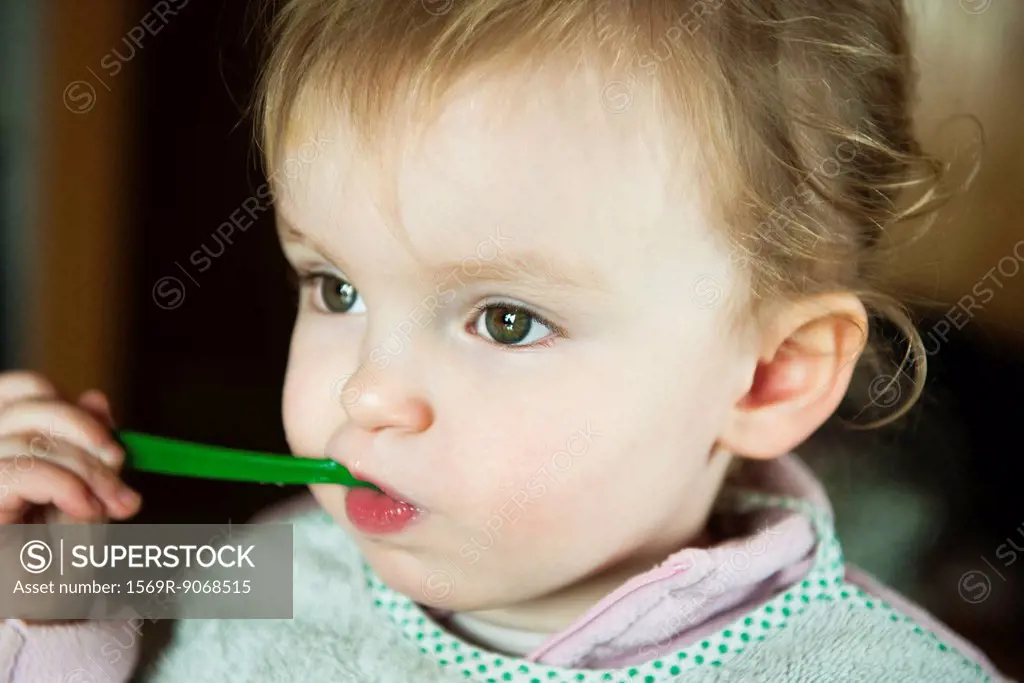 Toddler girl feeding herself, portrait