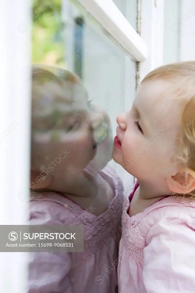Toddler girl looking through window