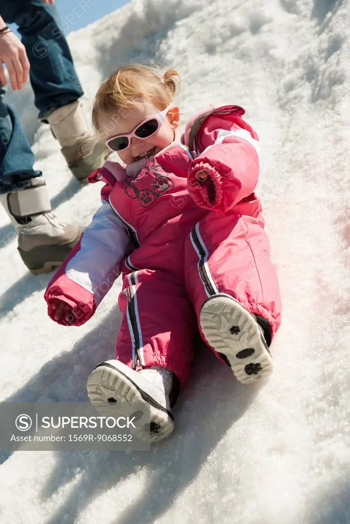 Toddler girl in snow_suit sitting on snow