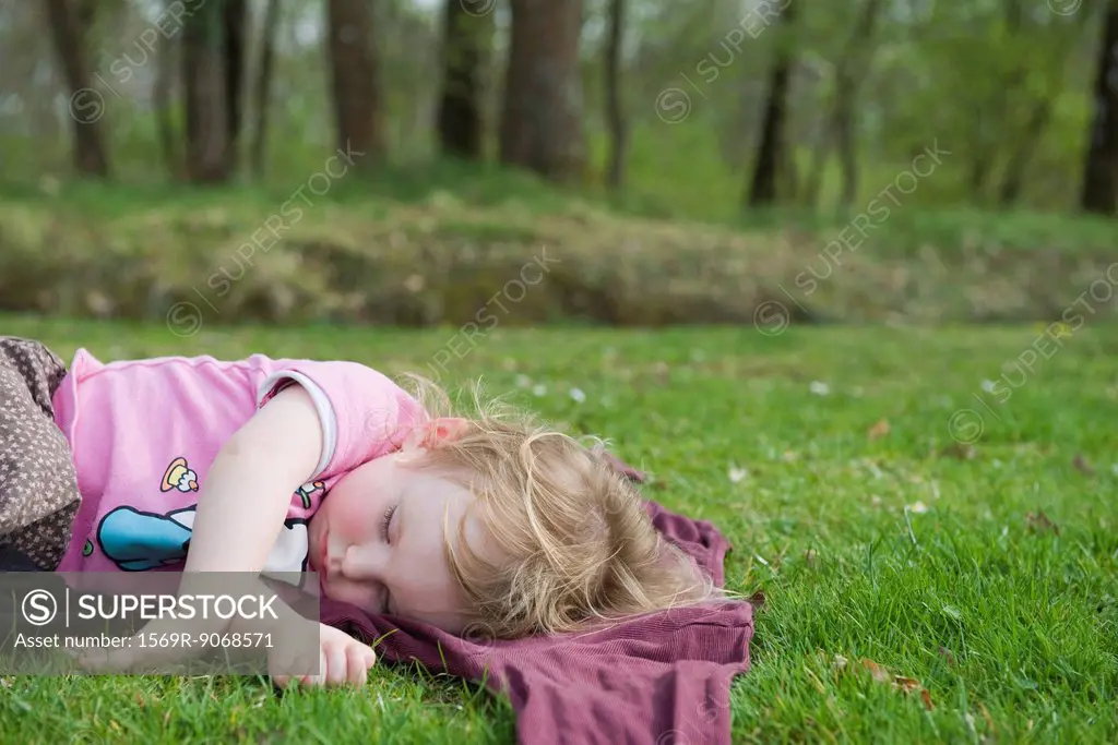 Toddler girl taking a nap outdoors