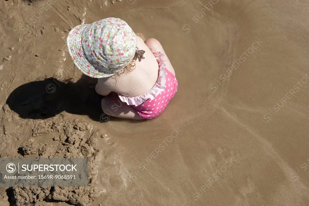 Toddler girl playing in sand at the beach