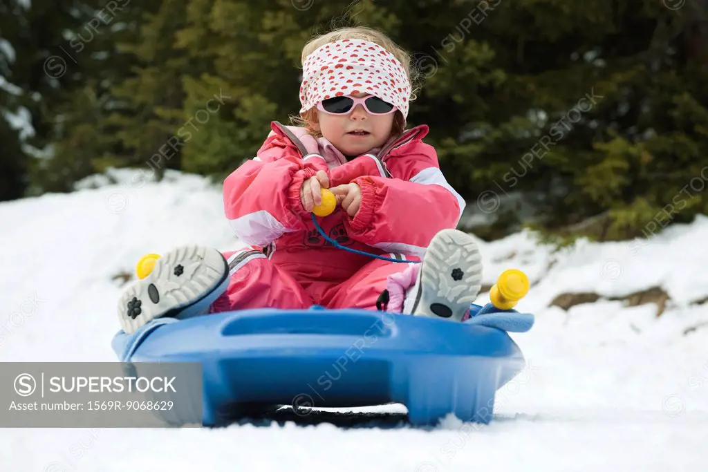 Toddler girl sitting on sled