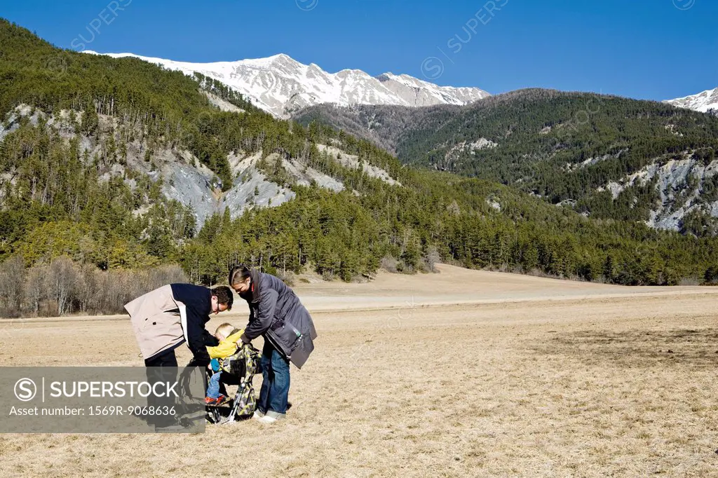 Parents getting child ready in baby carrier before going on hike