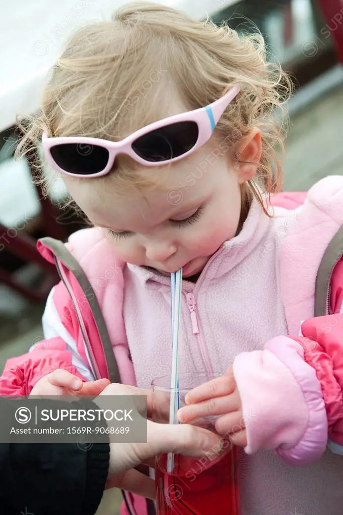 Toddler girl drinking juice with straw