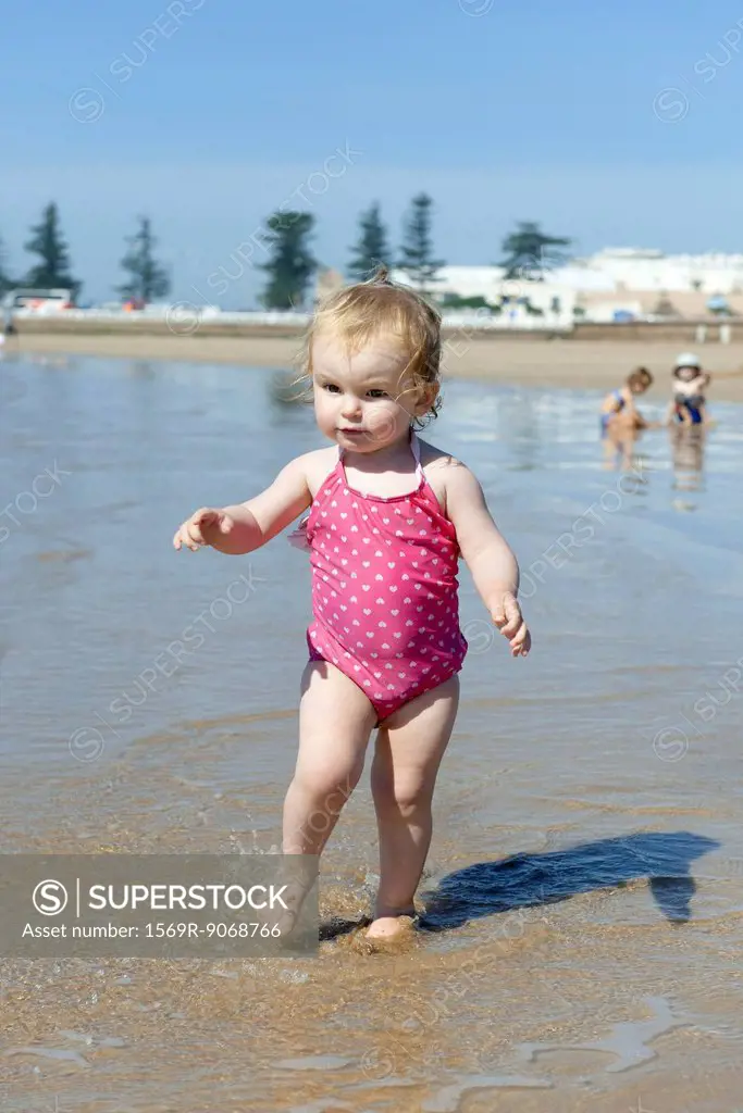 Toddler girl walking in surf at the beach