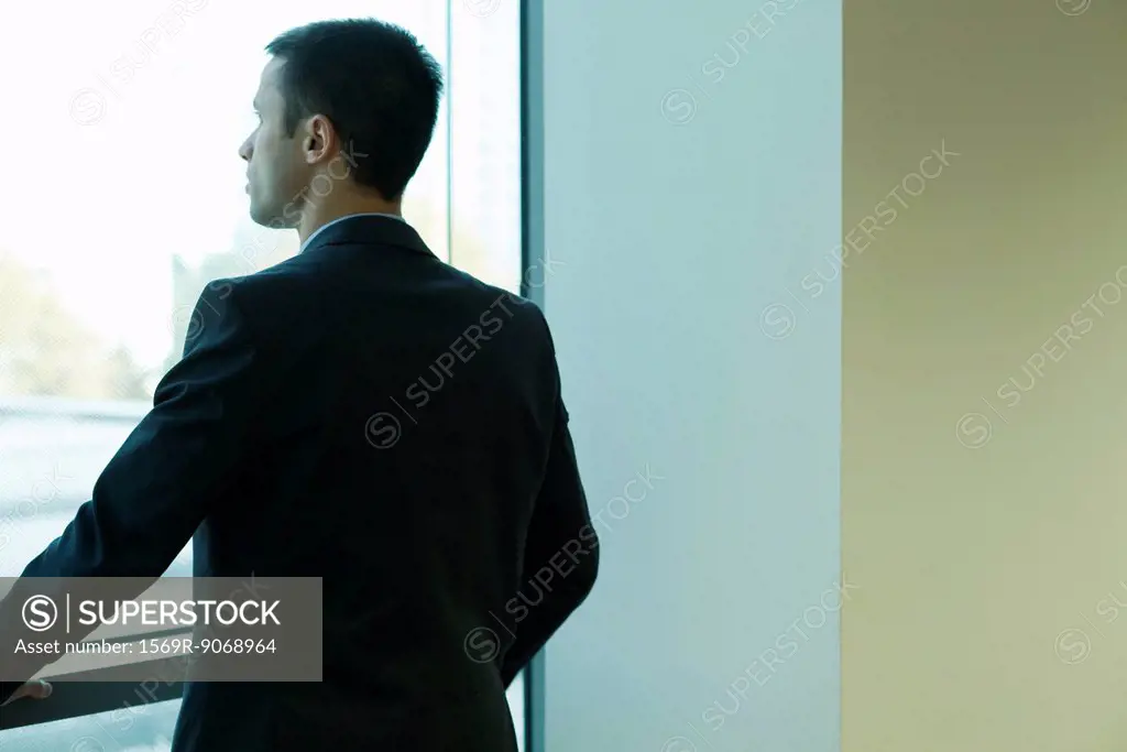 Young businessman looking out window in thought