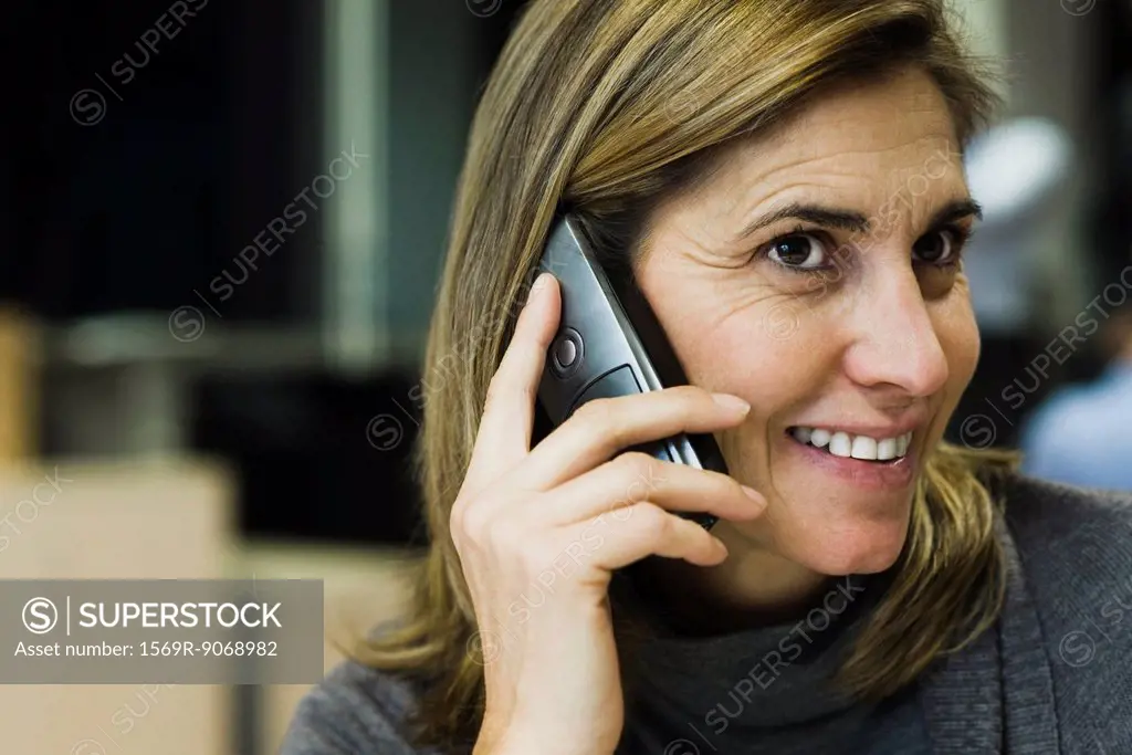 Woman talking on cell phone in office, portrait
