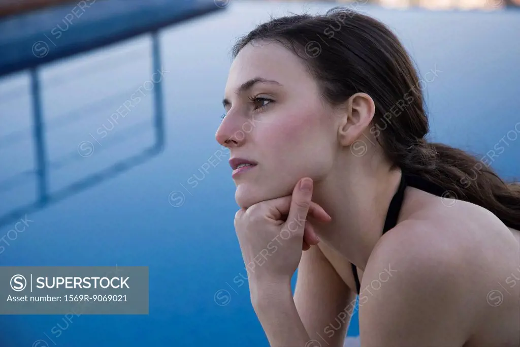Woman beside pool, looking away in thought