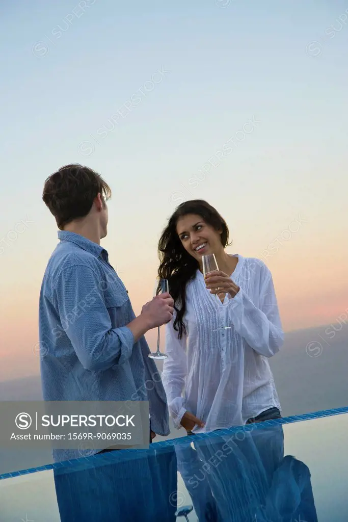 Couple standing at edge of infinity pool, enjoying champagne