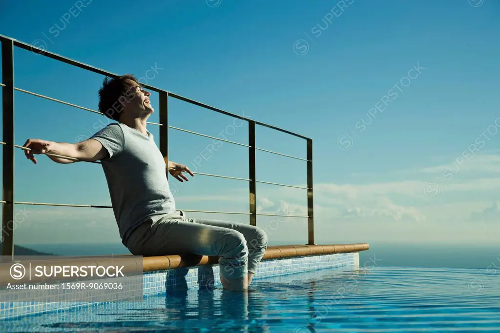 Man soaking feet in swimming pool