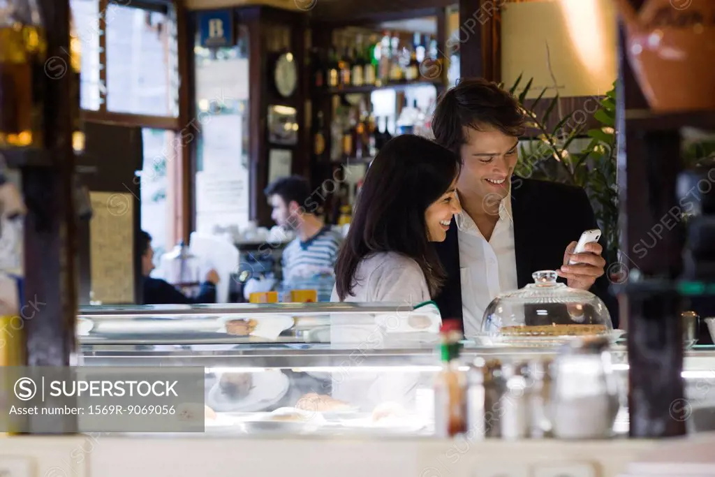 Couple looking at cell phone together in cafe