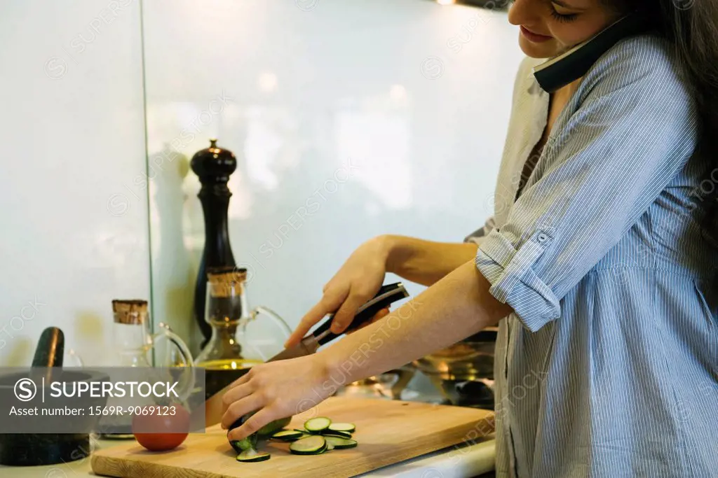 Woman talking on phone while chopping vegetables