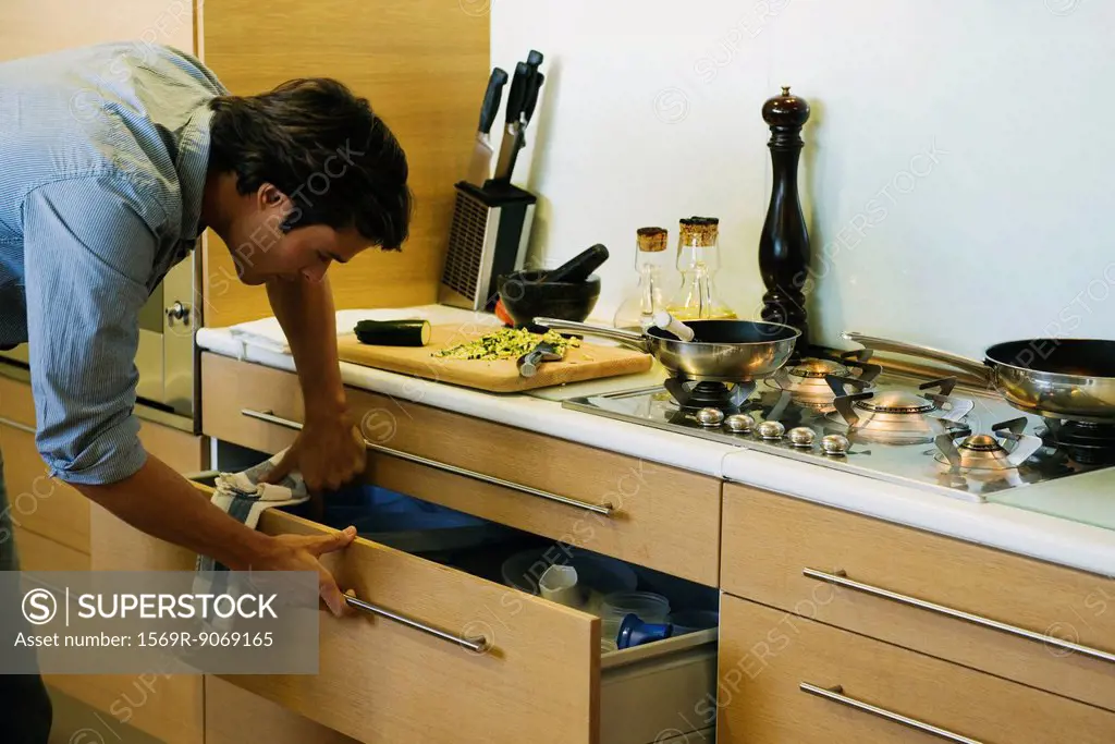 Man cooking in kitchen, looking in drawer