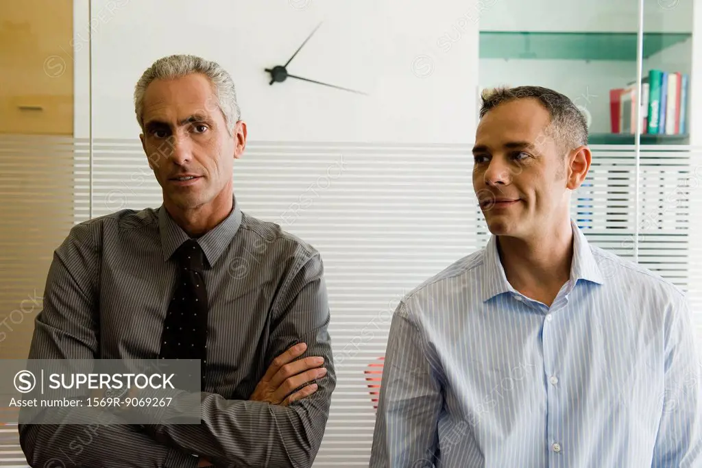 Businessmen standing side by side in office, portrait