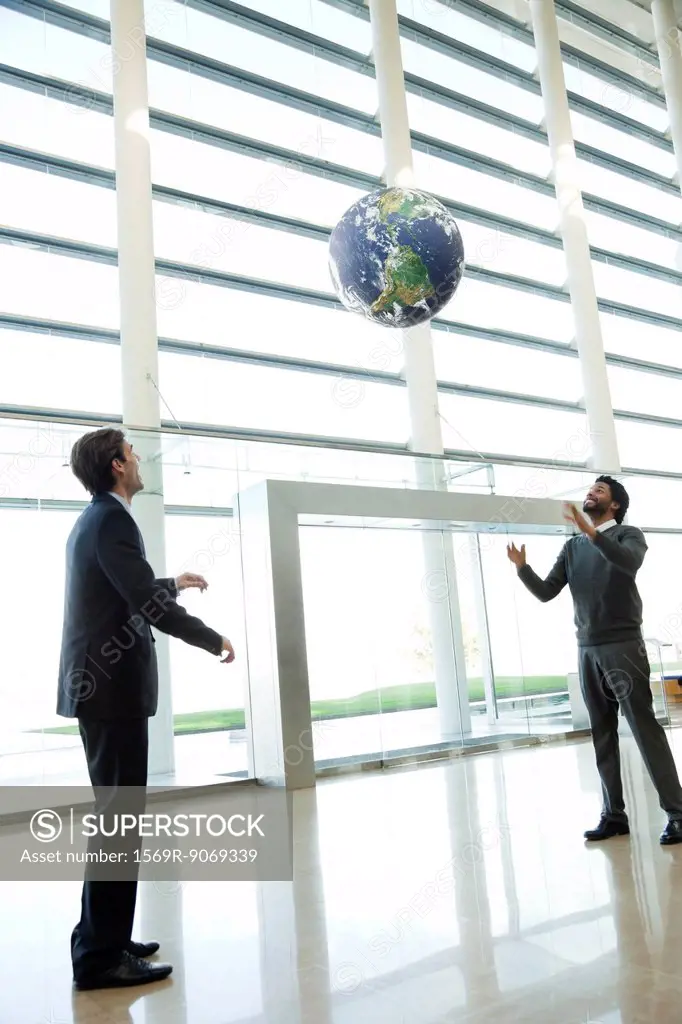 Businessmen throwing ball in lobby
