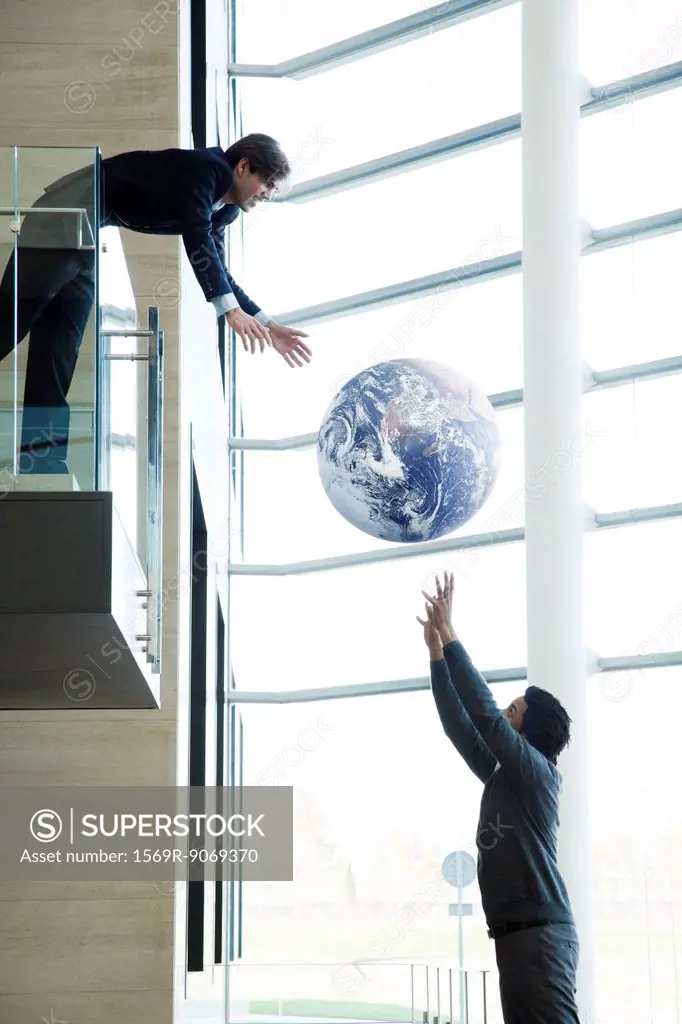 Colleagues throwing ball in lobby