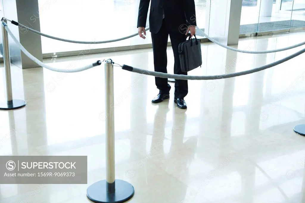 Businessman standing inside roped off area in lobby