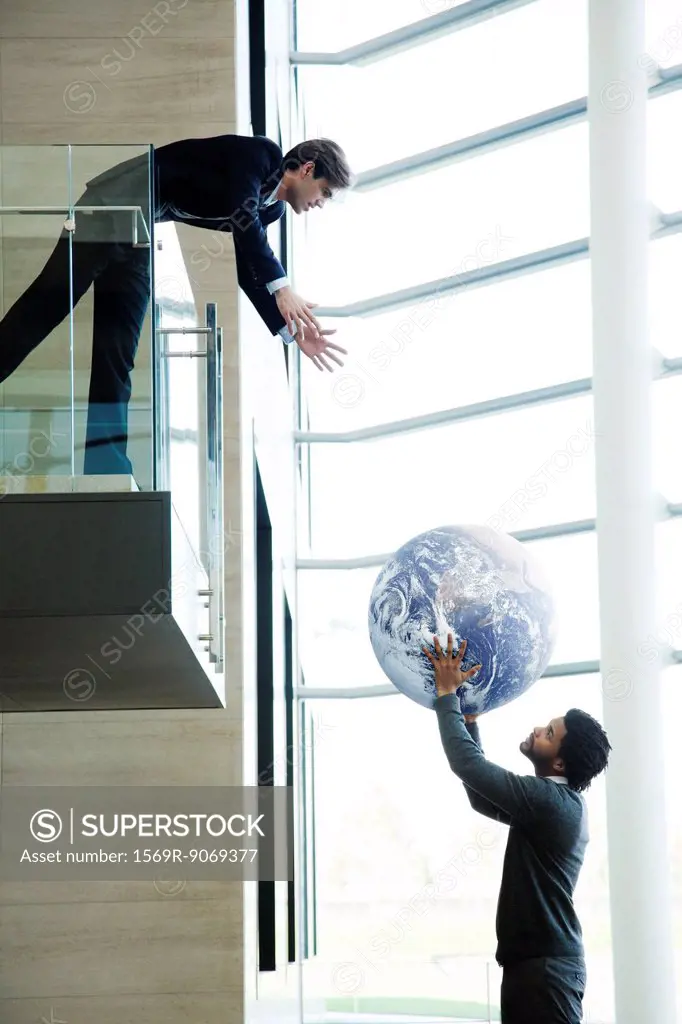Colleagues throwing ball in lobby