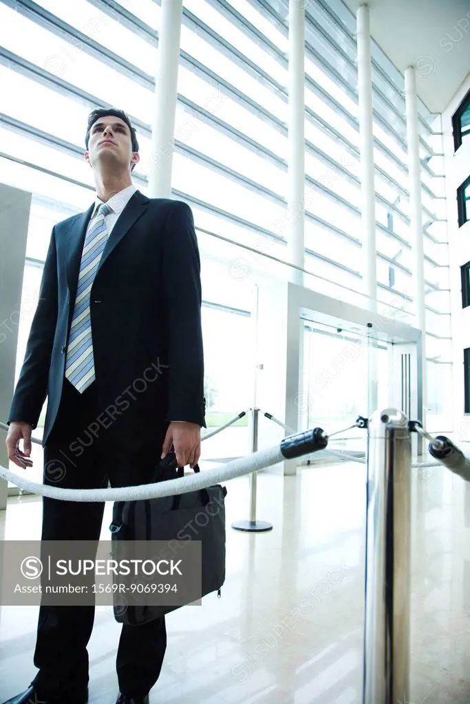 Businessman standing in lobby, looking up