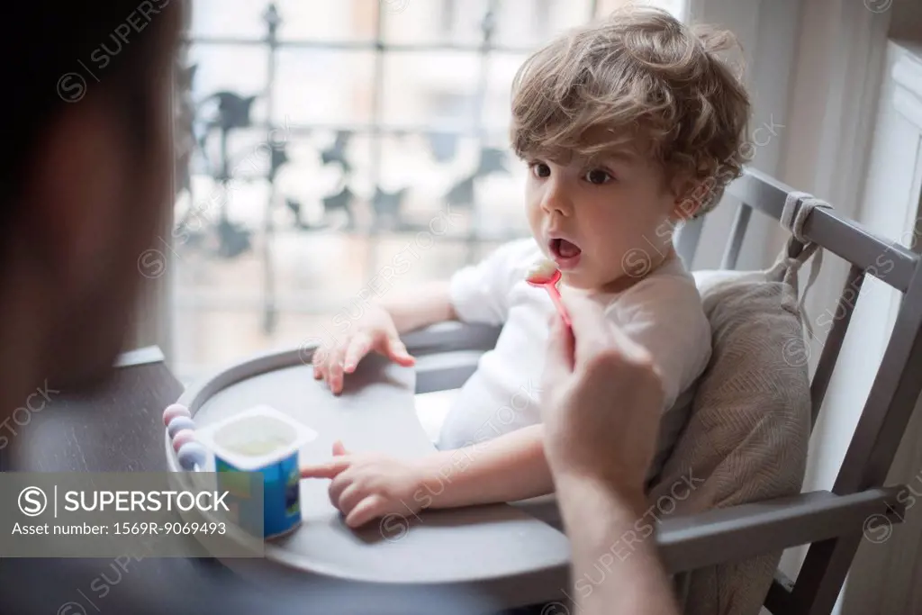 Toddler boy being fed yogurt