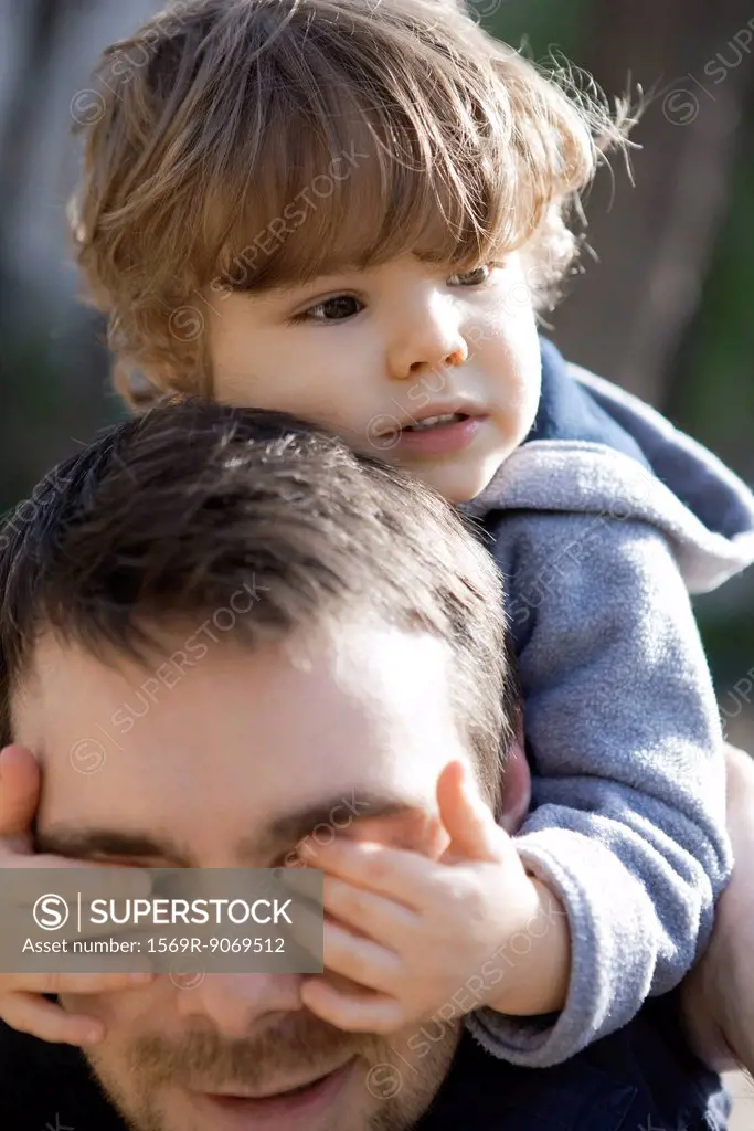 Toddler boy covering father´s eyes with his hands, portrait