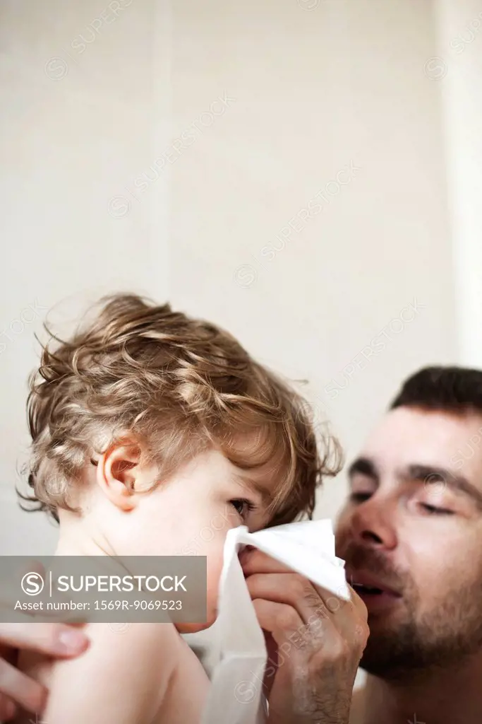 Father helping toddler son blow his nose