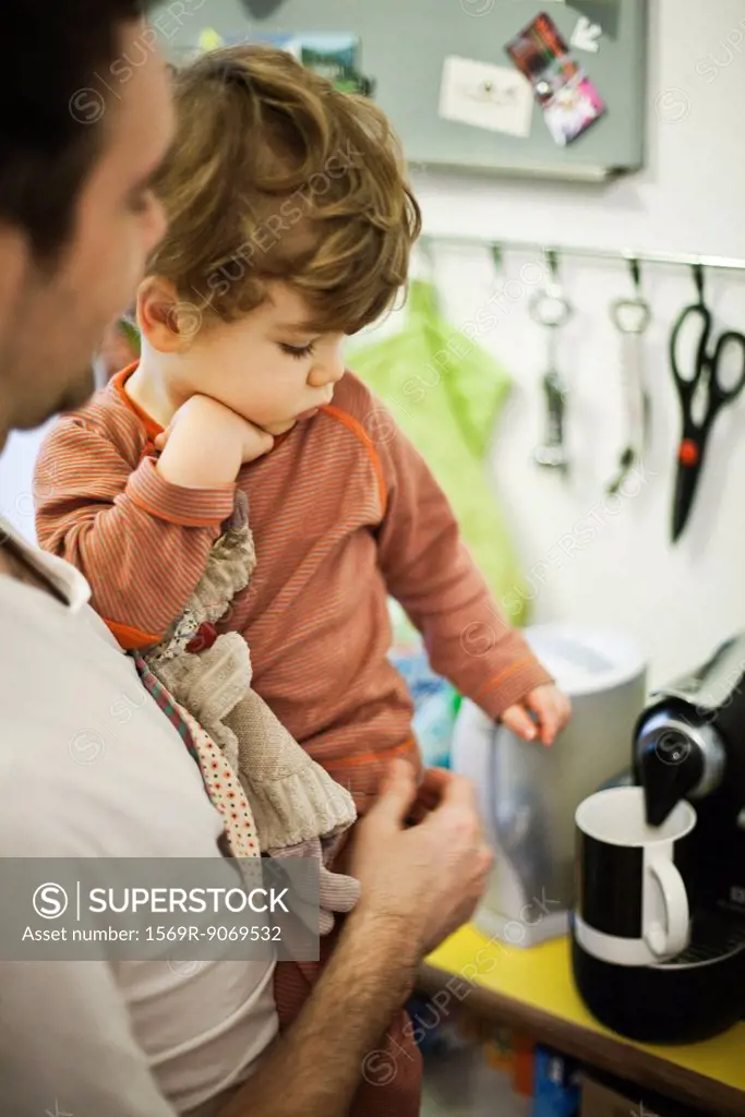 Father holding young son while preparing espresso