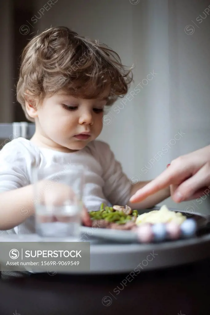 Toddler boy being told to eat his vegetables, cropped