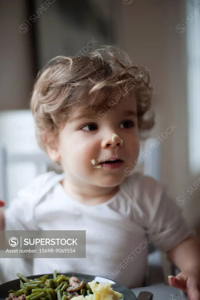 Toddler boy with food on his face, portrait