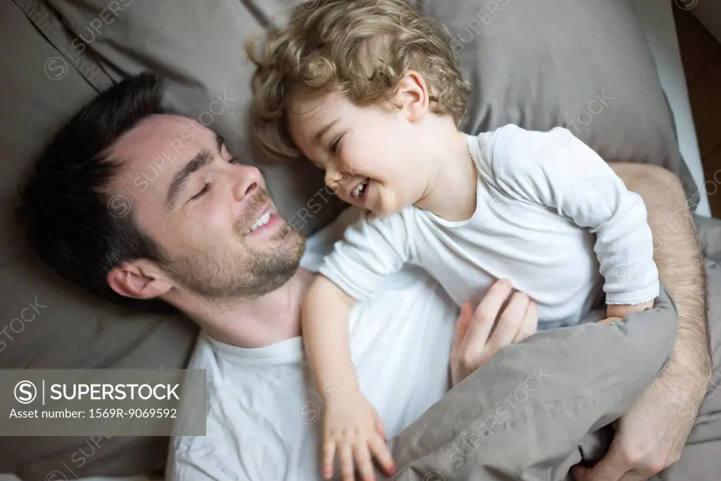 Father and young son relaxing together in bed, portrait