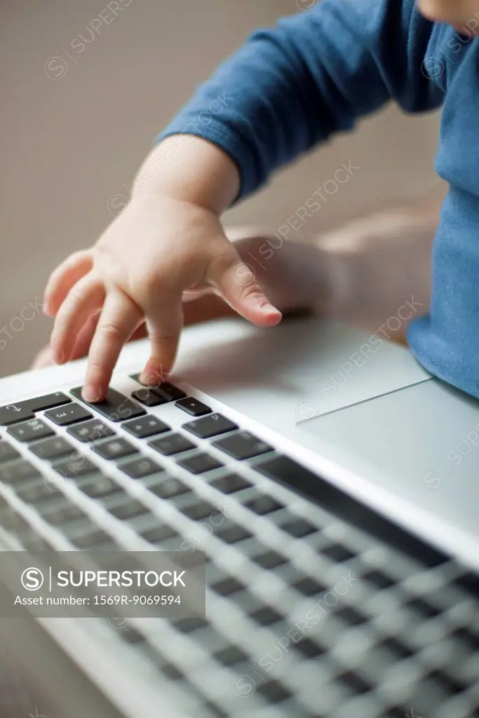 Child´s hand touching laptop keyboard