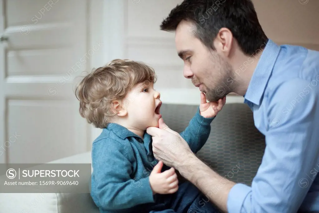 Father examining toddler son´s teeth, portrait