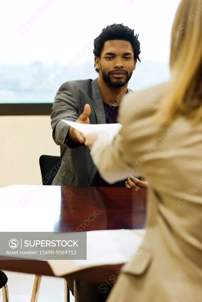 Man handing prospective employer his resume during job interview