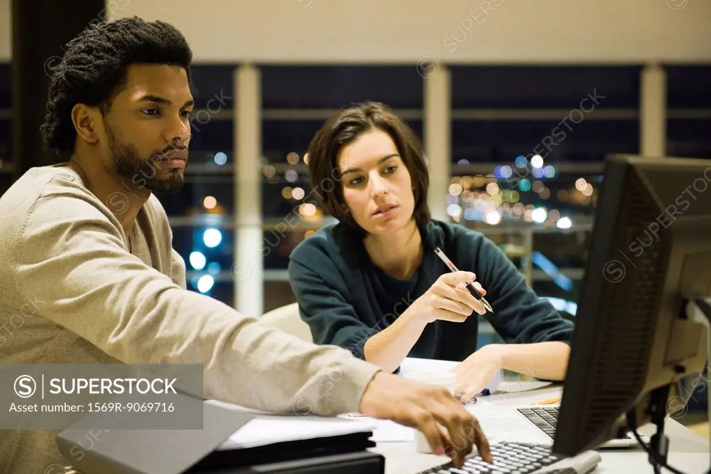 Colleagues working on project together in office at night