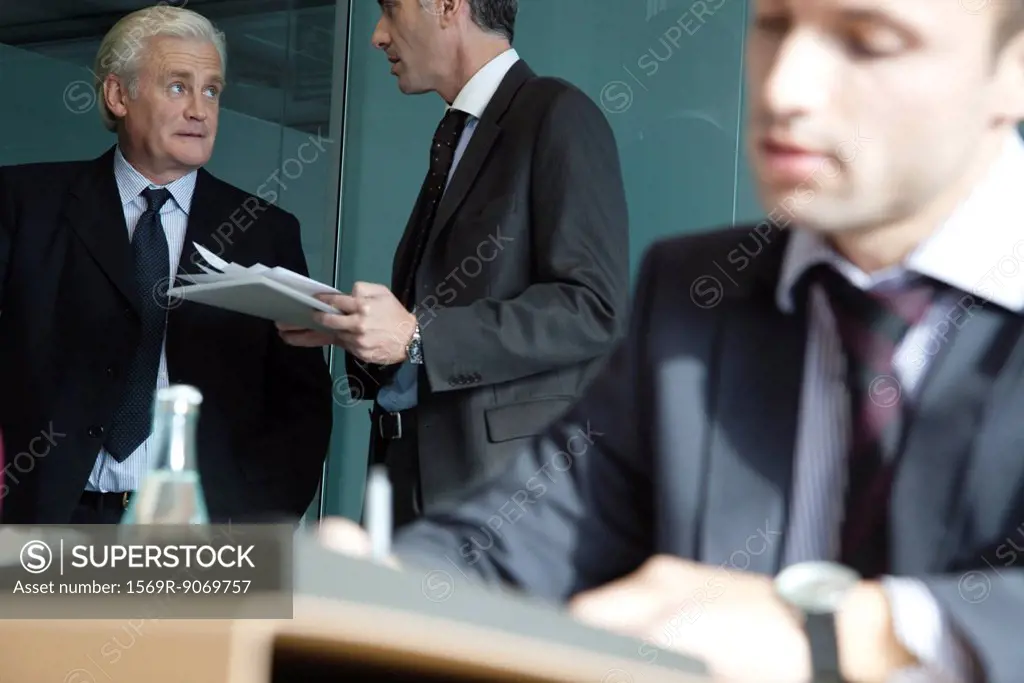 Executive in discussion, young businessman working in foreground