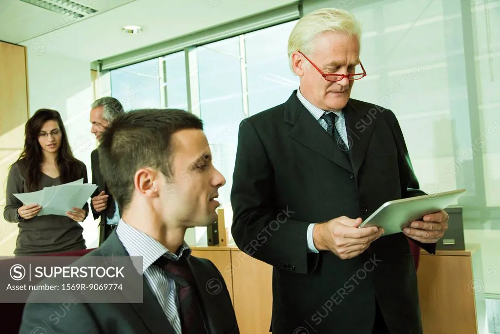 Executive using digital tablet with young associate