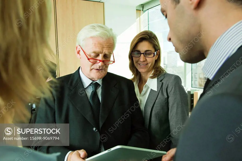 Mature executive trying out new digital tablet device with colleagues