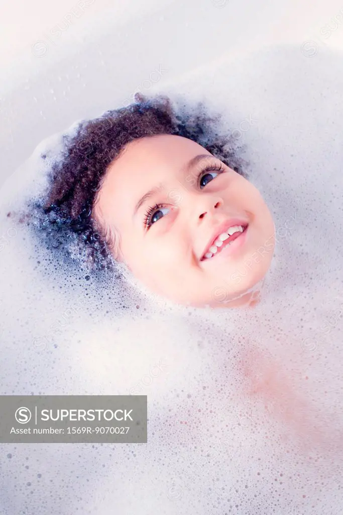 Little girl taking bath, head surrounded by soap sud
