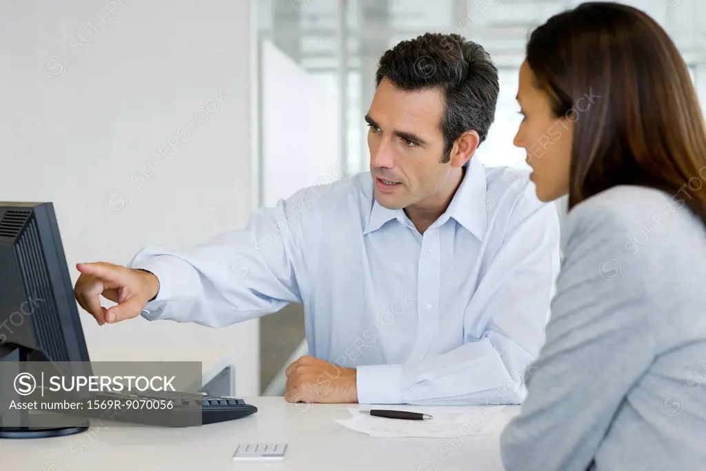 Financial advisor explaining to client data on desktop computer