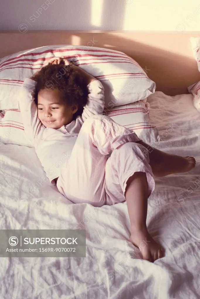 Little girl lying on bed in pajamas