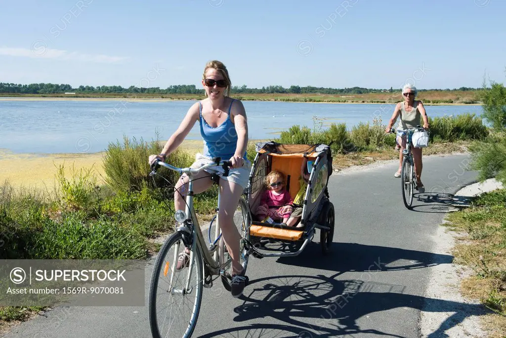 Multi_generation family enjoying bicycle ride, children sitting in bicycle trailer