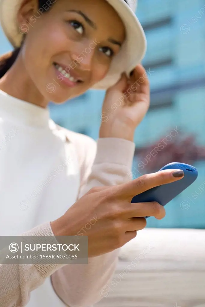 Woman with hat text messaging, low angle view