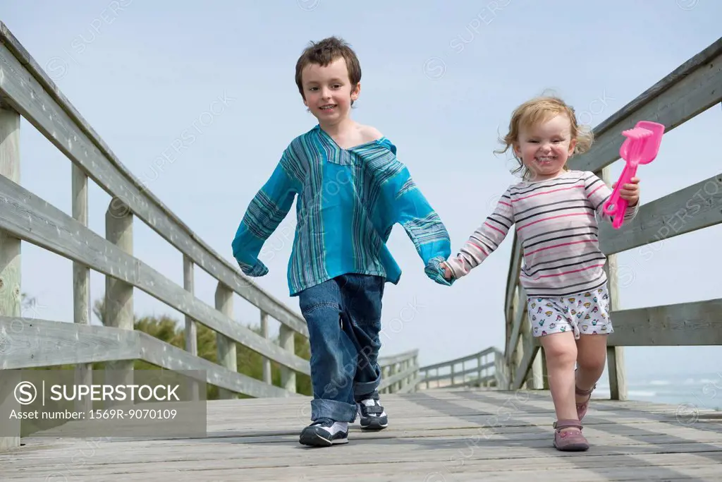 Young siblings walking hand in hand on boardwalk