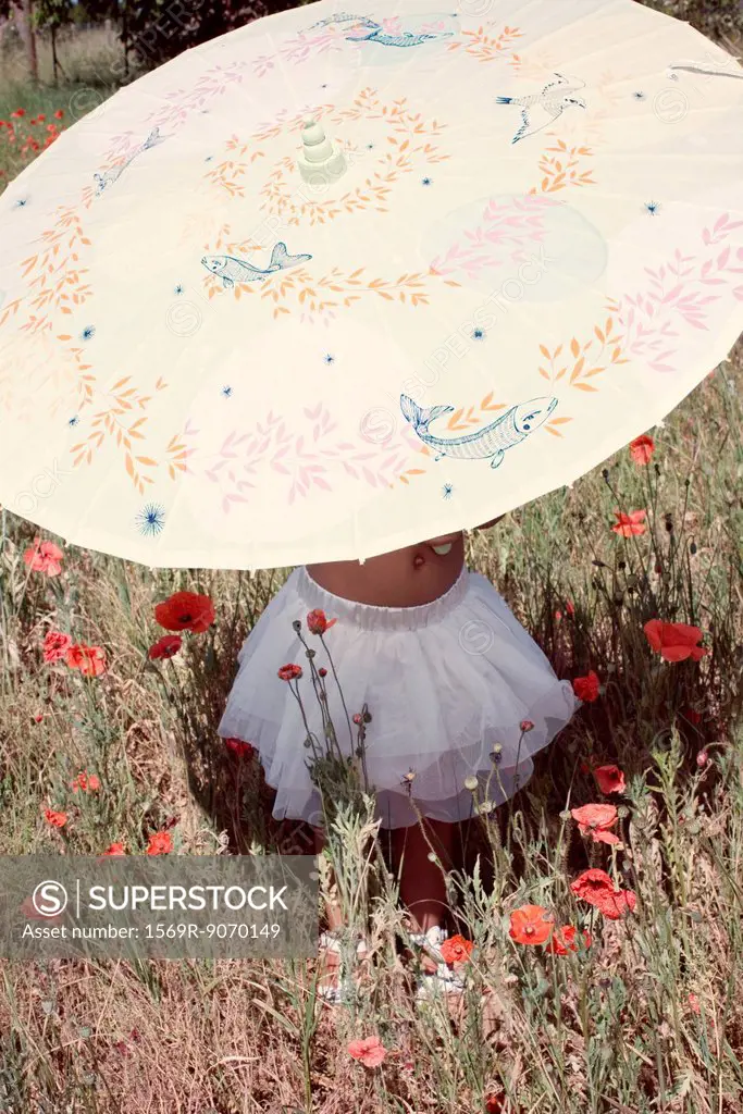 Little girl with parasol in meadow, mid section