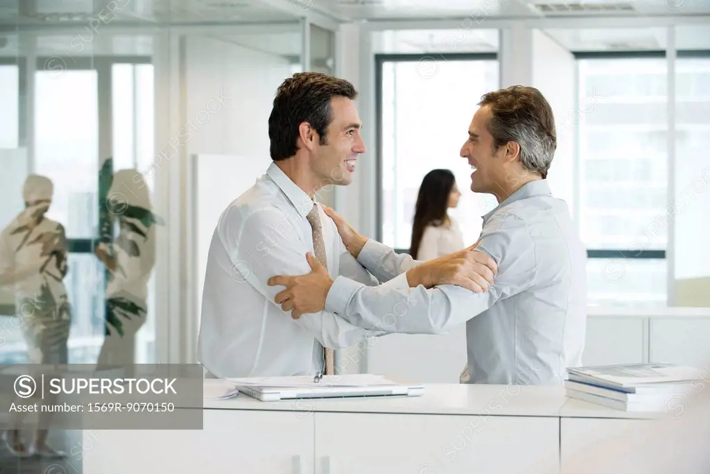 Businessmen holding each other´s arms with excitement